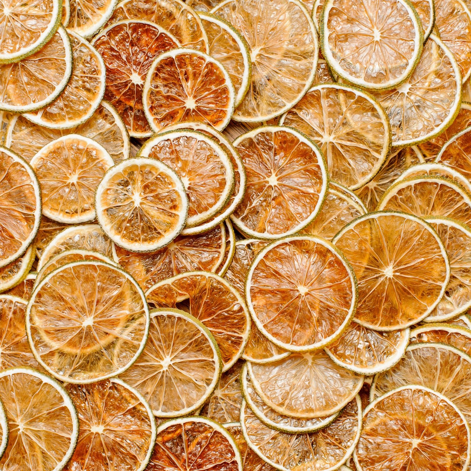 A close-up texture of numerous Super Bargain Shop dehydrated lime wheel garnishes, densely packed to fill the entire frame, showcasing variegated shades of green and brown.