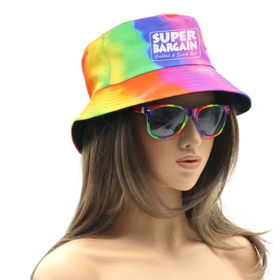 A mannequin wearing an adult-size Pride Bucket Hat - One Size by Super Bargain with the text "SUPER BARGAIN Cocktail & Snack Bar" on the front and matching rainbow sunglasses. The mannequin has long, wavy brown hair, making this a perfect summer accessory against a plain white background.