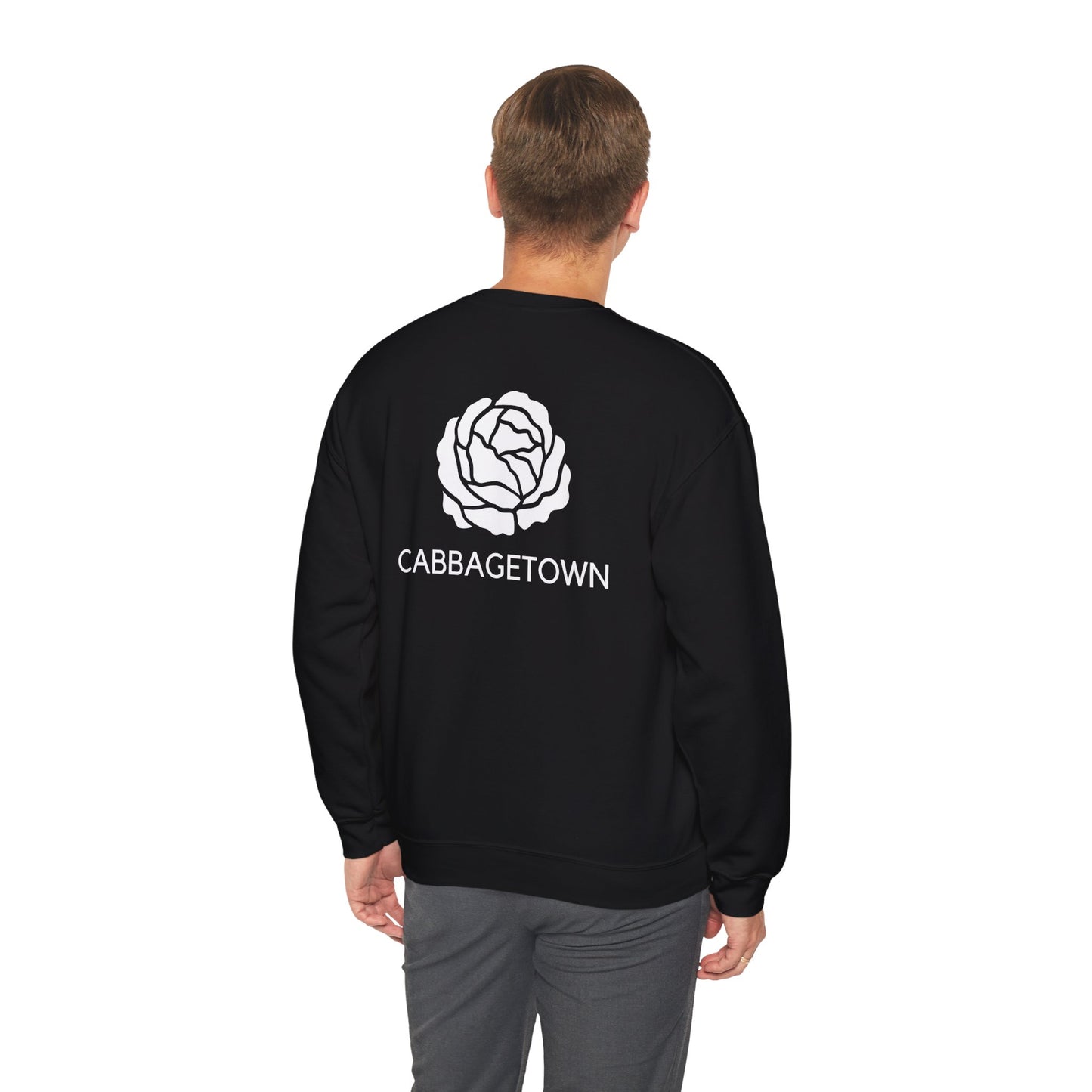 A man from behind wearing a black Unisex Heavy Blend™ Crewneck Monochrome Logo and Cabbagetown Sweatshirt with a white cabbage design and the word "CABBAGETOWN TORONTO" printed below it by Printify.