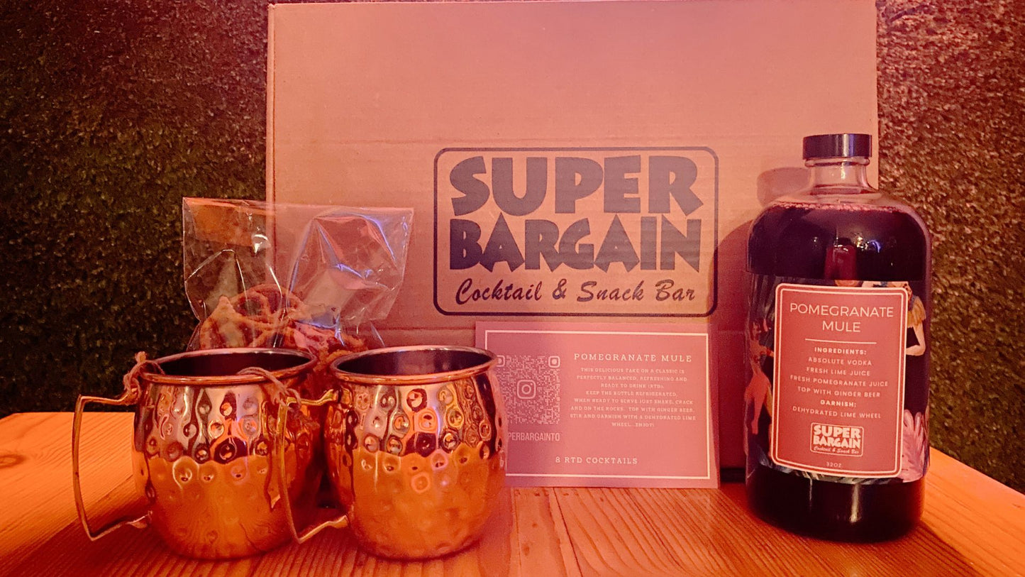 A cocktail and snack set featuring two copper mugs, a Pomegranate, Classic, Hibiscus Berry or Strawberry Mint Mule RTD Cocktail Box labeled "Mule RTD Cocktail Kit," and a box with the text "Super Bargain Cocktail & Snack Bar," displayed on a wooden surface with a dimly lit background.