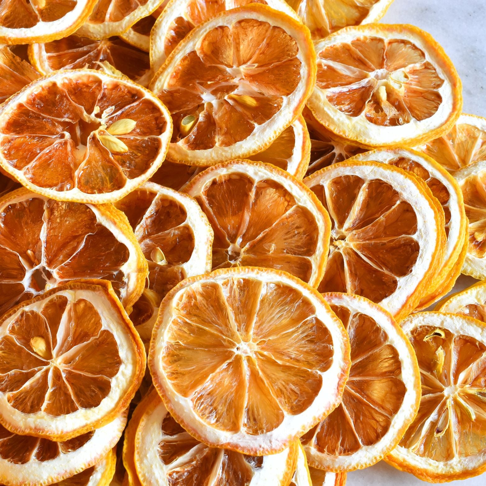 A close-up image of many thinly sliced Super Bargain Shop dehydrated lemon wheels arranged closely together, highlighting their vivid orange hues and intricate texture details.