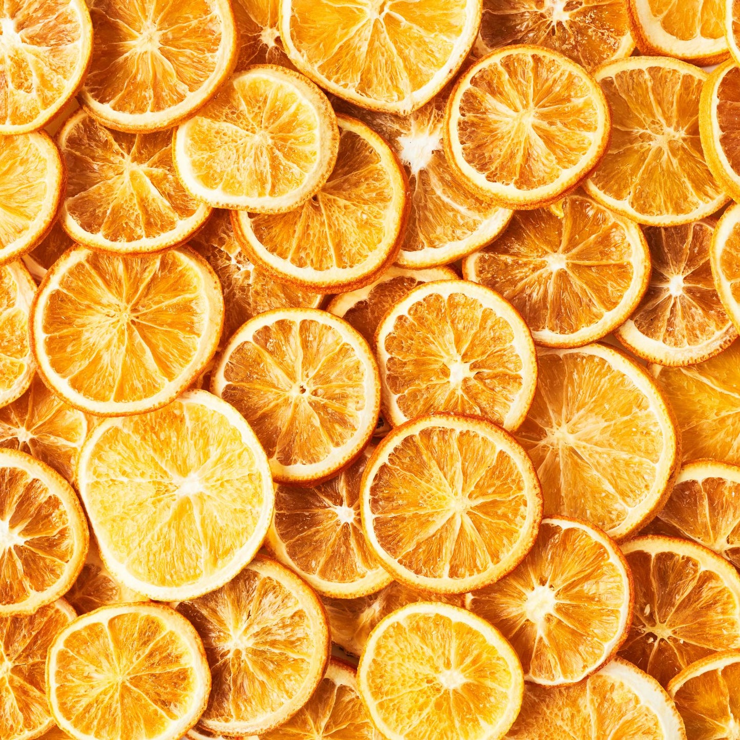 A vibrant close-up image of numerous Super Bargain Shop dehydrated orange wheel garnishes overlaid on each other, showcasing a range of rich orange hues and detailed textures.